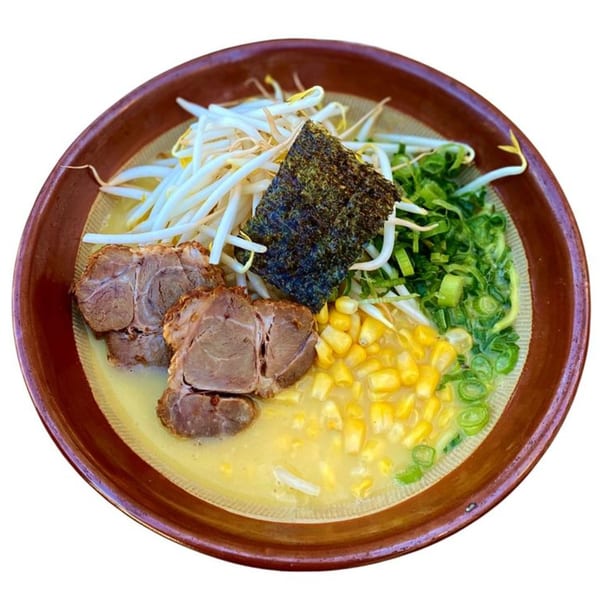 A bowl of Sapporo ramen with pork, corn, bean sprouts, green onions, and nori seaweed.