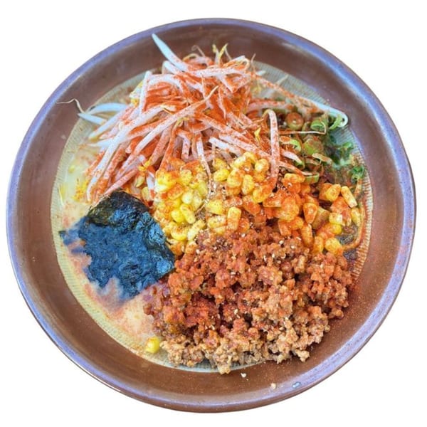 A bowl of Sapporo Ramen with bean sprouts, corn, seaweed, and ground meat, dusted with paprika.
